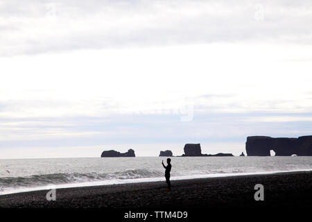 Tourist, Handy Foto am Strand Reynisfjara Island Stockfoto