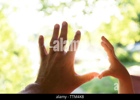 Vater und Kind berühren Finger gegen Sonnenlicht Stockfoto