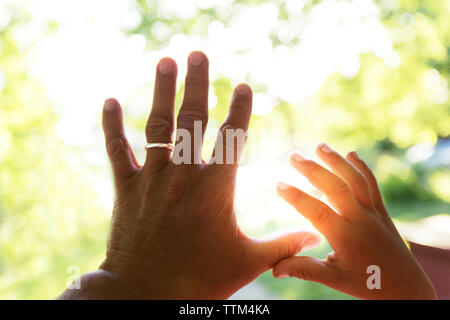 Vater und Kind berühren Finger gegen Sonnenlicht Stockfoto