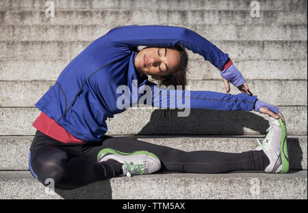 Mitte der erwachsenen Frau stretching auf Schritte Stockfoto