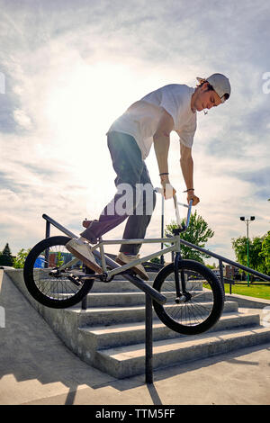 Reiter BMX Fahrrad am Geländer an skateboard Park gegen Himmel während der sonnigen Tag Stockfoto