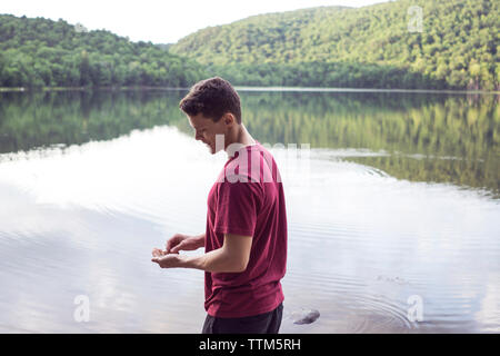 Männliche Wanderer genießen überspringen Felsen am Bergsee im Osten Kanada Stockfoto