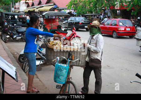 Siem Reap, Kambodscha - 30. April 2013: eine Frucht Verkäufer in Pub Street, Siem Reap mit einer Frau, die den Kauf von tropischen Früchten Stockfoto