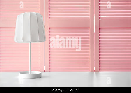 Stilvolle Lampe auf rosa Folding Screen Hintergrund Stockfoto