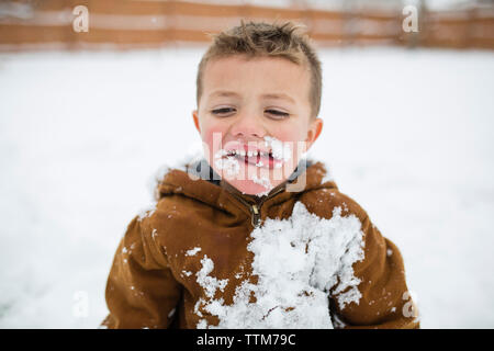 Cute boy heraus haften Zunge am schneebedeckten Feld Stockfoto