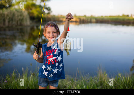 Portrait von Mädchen zeigen, ein Fisch beim Stehen gegen See Stockfoto