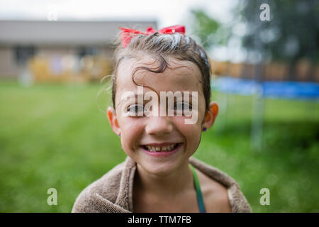 Portrait von glücklichen Mädchen im Handtuch im Hof gewickelt Stockfoto