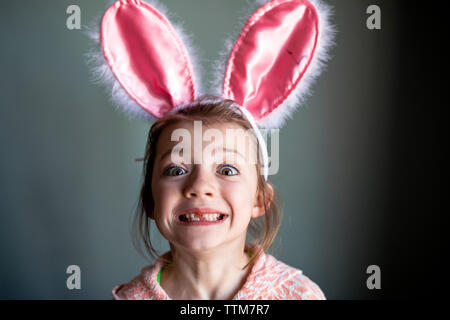 Portrait von verspielten Mädchen mit hasenohren kopfband und zeigt zur Lücke zu Hause Zahnriemen Stockfoto