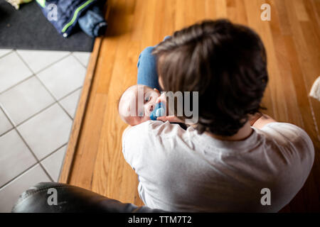 Hohe Betrachtungswinkel von Mutter Holding niedlichen Sohn sitzend auf Parkett zu Hause Stockfoto