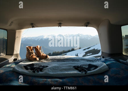 Wanderschuhe und Decke in Sports Utility Vehicle mit schneebedeckten Bergen im Hintergrund Stockfoto