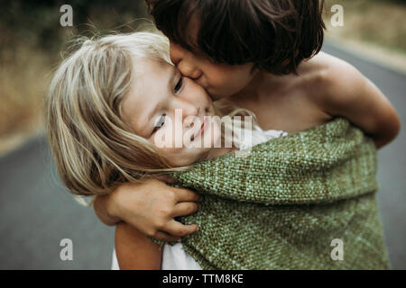 In der Nähe von Bruder küssen Schwester beim Stehen auf Landstraße Stockfoto