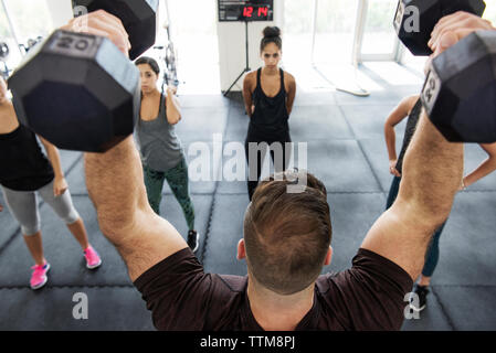 Kursleiter Hanteln bei der Erklärung der Athleten in crossfit Fitnessraum Stockfoto