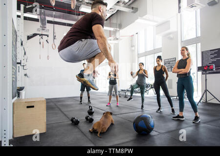 Kursleiter lehre Athleten beim Hund liegend in crossfit Fitnessraum Stockfoto