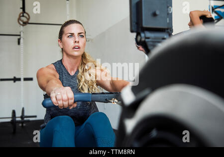 Konzentrierte Athleten trainieren auf Rudergerät in crossfit Fitnessraum Stockfoto