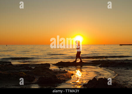 Seitenansicht silhouette junge Wandern am Strand bei Sonnenuntergang Stockfoto