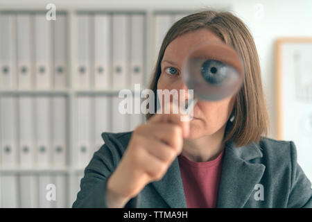 Geschäftsfrau mit Lupe, die finanzielle Überwachung, Prüfung und Bewertung von Jahresabschlüssen. Stockfoto