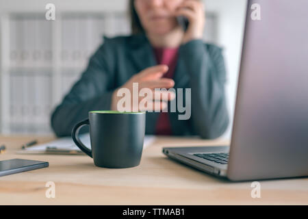Geschäftsfrau Gespräch am Handy während der Kaffeepause im Büro. Elegante Hündin business Person mit Smartphone und Kaffee Tasse. Stockfoto