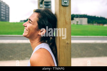 Glückliche Frau gegen Gymnastik bar im Park gelehnt Stockfoto