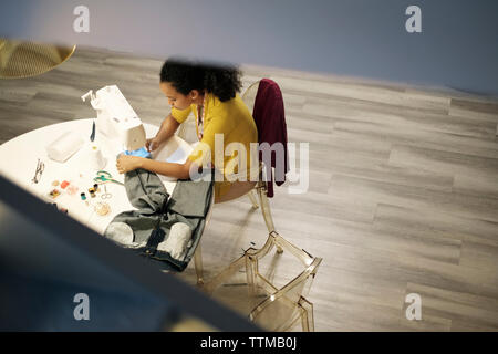 Hohe Betrachtungswinkel der weiblichen Unternehmer nähen Jeans mit der Nähmaschine am Tisch im Büro Stockfoto