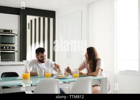 Glückliches junges Paar beim Frühstück am Esstisch in vermietung haus Stockfoto
