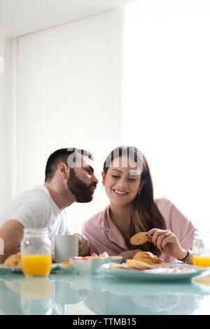 Lieben Freund küssen Freundin beim Frühstück am Esstisch in vermietung haus Stockfoto