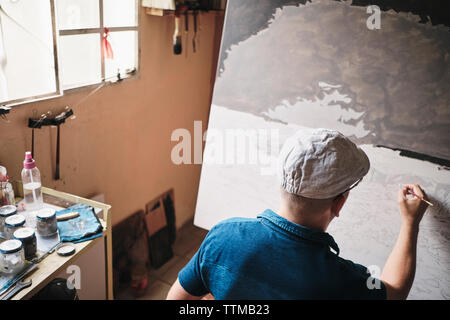 Mitte nach kubanischen Künstler malen Mit Pinsel auf Leinwand in seinem Studio Stockfoto