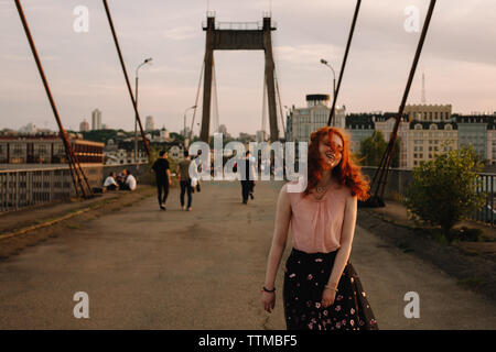 Junge fröhliche Frau zu Fuß über die Brücke in die Stadt Stockfoto