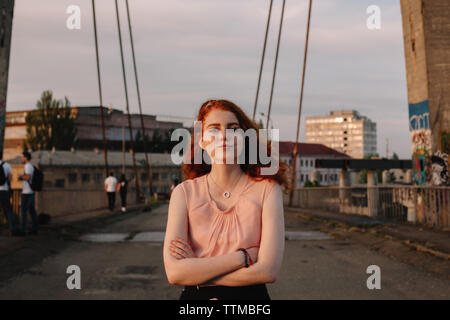 Porträt der jungen Frau mit gekreuzten Armen stehen auf der Brücke in der Stadt Stockfoto