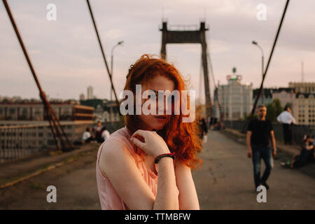 Portrait von nettes junges Mädchen mit roten Haaren steht auf der Brücke in der Stadt Stockfoto