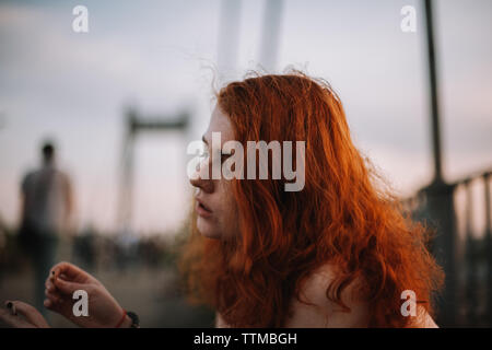 Junge Frau mit Zigarette und Streichholz beim Sitzen auf der Brücke Stockfoto