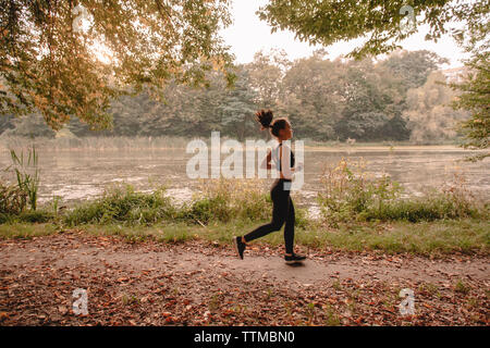 Seitenansicht der jungen Frau Joggen im Wald am See Stockfoto