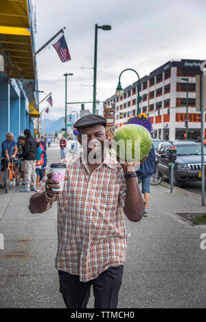 USA, Alaska, Anchorage, ein lokaler Mann Spaziergänge durch die Straßen der Innenstadt tragen eine Wassermelone Stockfoto