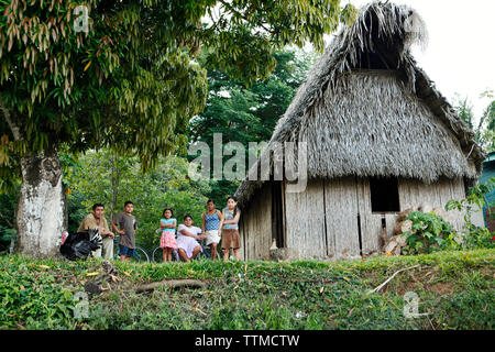 BELIZE, Punta Gorda, Toledo, eine Familie sitzt vor ihrem Haus auf der Seite der Straße in der Nähe des Li Punit Ruinen Stockfoto