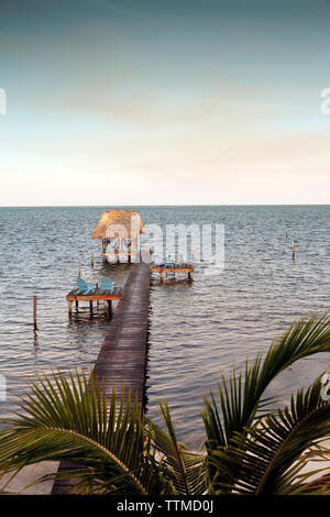 BELIZE, Caye Caulker, Touristen auf einem Pier entspannen am Wasser bei Sonnenuntergang Stockfoto