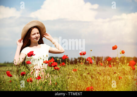 Schöne Mädchen mit Hut im Mohnfeld auf sonnigen Sommertag Stockfoto