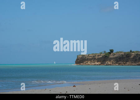 Einen karibischen Strand mit kristallklarem, blauen Wasser. Schönen blauen Himmel und unberührten, goldenen Sand. Segelyacht im Hintergrund Stockfoto