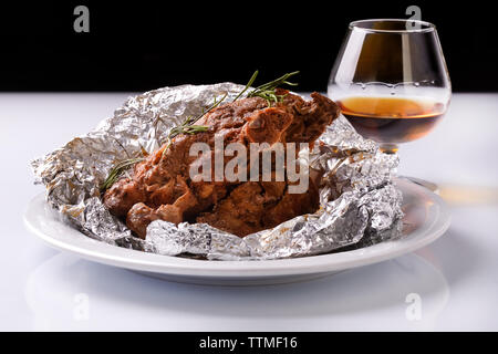 Lamm vom Grill Rippen auf der Platte in Aluminiumfolie mit Brandy oder Cognac bedeckt Stockfoto