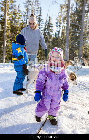 USA, Oregon, Biegen, ein Junge und ein Mädchen spielen mit den Schlittenhunden am Mt. Bachelor Stockfoto