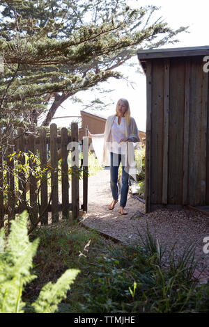 USA, Kalifornien, Big Sur, Esalen, Frau geht durch ein Tor neben dem kleinen hölzernen Jurte am Esalen Institut Stockfoto