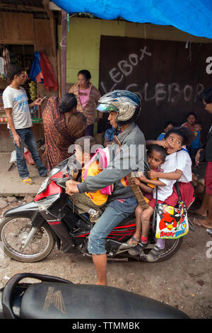 Indonesien, Flores, ein Vater und seine drei Söhne fahren mit dem Motorrad an der Bajawa Markt in Bajawa Stockfoto