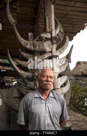 Indonesien, Flores, Bena Dorf, ein Mann steht vor seinem Haus, das in Kuh Hörner, die ihm angeboten wurden, als er sein Haus gebaut geschmückt ist Stockfoto