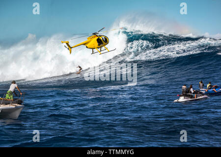 USA, Hawaii, Maui, Backen, einem schwebenden Hubschrauber über den großen Wellen und Surfer an Peahi auf dem Northshore Stockfoto