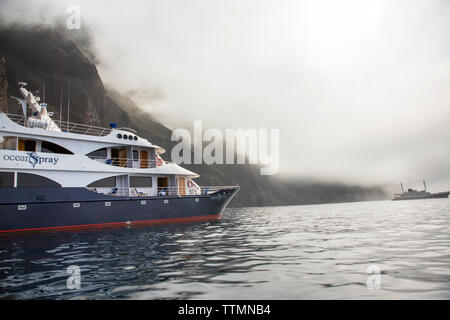 GALAPAGOS, Ecuador, die Insel Isabela, Punta Vicente Roca, M/C Ocean Spray aus der dramatischen steilen vulkanischen Klippen der Insel Isabela verankert Stockfoto