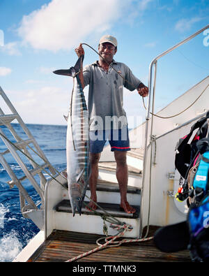 Fidschi, nördlichen Lau Inseln, ein Matrose hält eine große tropische Fische auch als Ono, als Wahoo, Kingfish oder Tiger Fisch bekannt Stockfoto
