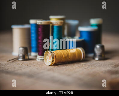 In der Nähe der bunten Spulen mit fingerhüte auf Holztisch in der Werkstatt Stockfoto