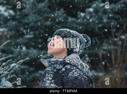 Verspielte Junge heraus haften Zunge bei Schneefall Stockfoto