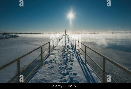 Schnee bedeckt Pier über den See gegen Sky Stockfoto