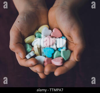 7/8 Hände der boy Holding bunte Herzen Form Süßigkeiten zu Hause Stockfoto