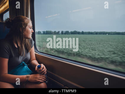 Junges Mädchen auf der Suche durch das Fenster während der Fahrt im Zug Stockfoto