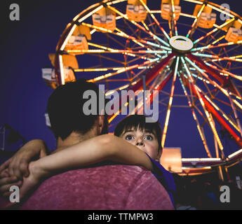 Close-up von Vater, Sohn von beleuchtete Riesenrad im Vergnügungspark bei Nacht Stockfoto